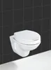 A white wall-mounted toilet with a closed lid is shown against a black tiled wall and a white tiled floor. Produktbild-Vorschau