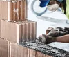 A construction worker is using a reciprocating saw to cut a brick. Voir les images du produit