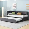 A dark gray upholstered daybed with a pull-out trundle bed is shown in a room with light blue walls and a tall white floor lamp. Produktbild-Vorschau