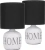 Two identical table lamps with black fabric shades and white ceramic bases featuring the word 'HOME' in gray. Náhľad obrázku produktu