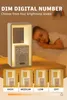 A child sleeping in bed next to a bedside lamp that also functions as an alarm clock. Produktbild-Vorschau