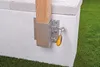 A wooden post is being attached to a concrete structure with a metal bracket and a wrench. Voir les images du produit