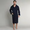 A man wearing a blue hooded bathrobe stands against a plain gray background. Produktbild-Vorschau