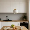 A modern kitchen scene with a pendant light hanging over a wooden table with breakfast items. Náhled obrázku produktu