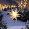 A lit star decoration stands in a snowy garden at night, with trees decorated with fairy lights in the background. Produktbild-Vorschau