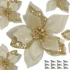 A collection of artificial gold and cream poinsettias with glitter accents, arranged on a white background. Several are in focus, with others slightly blurred in the background. A small group of silver clips is visible in the bottom right corner. Produktbild-Vorschau