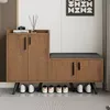 A wooden shoe cabinet with a padded bench on top, placed in a hallway or entryway. Produktbild-Vorschau