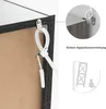 Close-up of a picture frame's back with an anti-tip device attached, and inset diagrams showing how to install it. Náhľad obrázku produktu