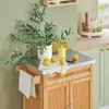 A kitchen cart with a stainless steel top, displaying lemons, an olive branch in a vase, and bottles of oil. Produktbild-Vorschau