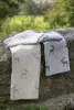 Two blankets with deer pattern are draped over a stone wall with greenery in the background. Produktbild-Vorschau