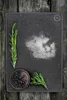 A dark cutting board with rosemary, juniper berries, and salt on a wooden background. Anteprima dell’immagine prodotto