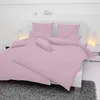 A neatly made bed with pink bedding, including pillows and a bolster pillow, set against a white wall with decorative spheres and lamps. Produktbild-Vorschau