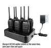 A set of six black walkie-talkies charging in a black charging dock, with a power adapter plugged into a wall socket. Náhled obrázku produktu