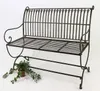 A metal garden bench on a white background with a small potted plant next to it. Produktbild-Vorschau