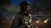 A soldier in tactical gear stands in a dimly lit, outdoor environment with a vehicle and fires in the background. Produktbild-Vorschau