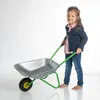 A young girl is pushing a toy wheelbarrow. Produktbild-Vorschau