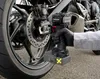 A person is using a cordless impact wrench to work on the rear wheel of a motorcycle. Produktbild-Vorschau