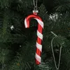 A red and white striped candy cane ornament hangs on a Christmas tree. Produktbild-Vorschau