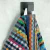 A colorful patterned towel hanging on a black hook against a light gray wall. Produktbild-Vorschau