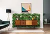 A living room scene featuring a mid-century modern credenza against a wall covered in a green artificial plant installation. Produktbild-Vorschau