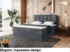 A bedroom scene featuring a large, upholstered bed with a headboard, mattress, and topper. The room is decorated with a large plant, artwork, and a side table. Produktbild-Vorschau