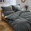 A neatly made bed with gray bedding and pillows.