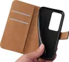 A hand holding a black phone case with a brown wallet attached. Produktbild-Vorschau