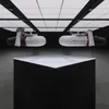 Two Aqua Marina BlueDrive X PRO Power Fin units are displayed above a black pedestal with a white top surface in a studio-like setting with overhead lighting. Podgląd zdjęcia produktu