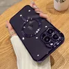 A hand holding a dark purple iPhone case with a MagSafe ring and camera protection, placed on a wooden table. Produktbild-Vorschau