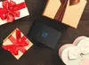 A black external hard drive is placed on a dark wooden surface surrounded by gift boxes. Produktbild-Vorschau