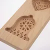 A close-up view of a wooden cookie mold with carved designs of a bell and a heart. Náhľad obrázku produktu