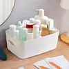 A white storage box filled with various toiletries and cosmetic bottles is placed on a wooden surface. Produktbild-Vorschau