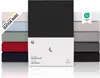 A stack of folded fitted sheets in various colors, with a product box in the foreground. Produktbild-Vorschau
