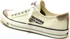 A side view of a white canvas sneaker with tan accents. Voir les images du produit