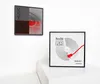 Two framed art pieces are displayed on a white wall, one hanging and one on a white pedestal. Produktbild-Vorschau