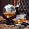 A globe-shaped decanter filled with amber liquid, two matching glasses, and whiskey stones on a wooden surface, with a tufted leather chair in the background. Náhľad obrázku produktu