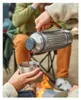 People are camping and pouring coffee from a thermos into a cup near a campfire. Voir les images du produit