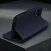 A dark blue leather iPhone case with red stitching is shown in a studio setting, propped up to display its stand function. Produktbild-Vorschau