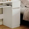 Close-up view of a white desk with a keyboard tray and a drawer, next to a bed. Podgląd zdjęcia produktu