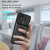 A hand holding a black phone case with a ring stand, with a blurred background of a dining area. Produktbild-Vorschau
