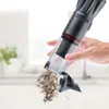 A hand is holding a handheld vacuum cleaner and emptying its contents onto a surface. Produktbild-Vorschau