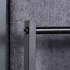 A close-up view of a black metal towel rack with a grey towel hanging on it. Náhľad obrázku produktu