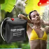 A woman is showering outdoors with a portable camp shower. Podgląd zdjęcia produktu
