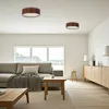A modern living room with a sofa, coffee table, and a sideboard, featuring two ceiling lights. Produktbild-Vorschau