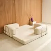 A beige sofa bed is shown in a room with a wooden wall and a small side table with a vase and a cup. Anteprima dell’immagine prodotto