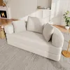 A cream-colored sofa bed with pillows is shown in a living room setting, with a fireplace and cabinets in the background. Náhled obrázku produktu