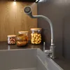 A modern kitchen sink area with a flexible gray faucet and jars of food items in the background. Podgląd zdjęcia produktu