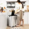 A woman is in a kitchen, about to throw a cutting board into a stainless steel trash can. Podgląd zdjęcia produktu