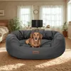 A dog is lying in a dog bed in a living room setting. Voir les images du produit