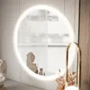 A modern vanity area with a circular illuminated mirror, decorative busts, and a gold pendant lamp. Produktbild-Vorschau